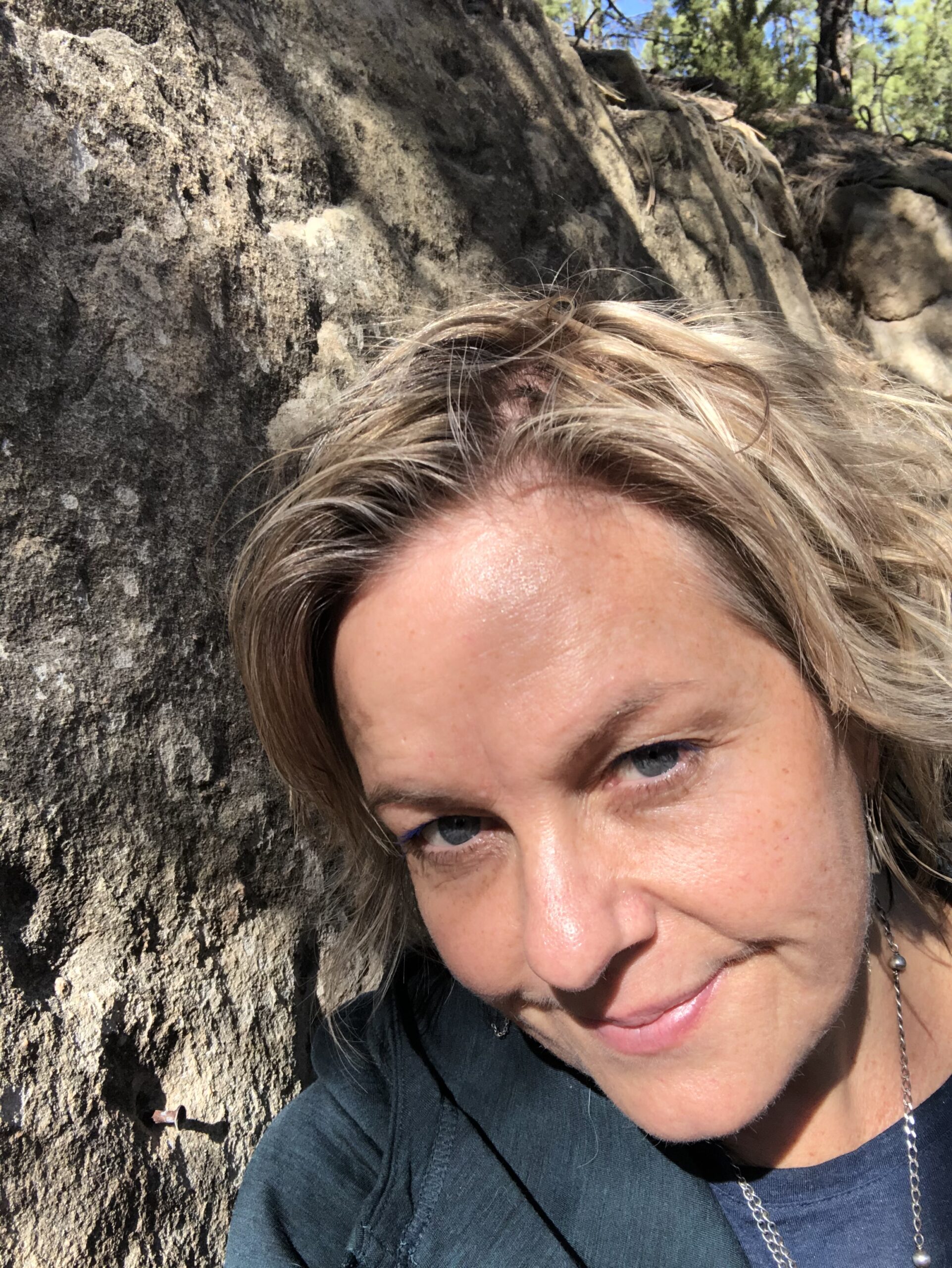 Blair leaning against a tree with a ray of sun on her face
